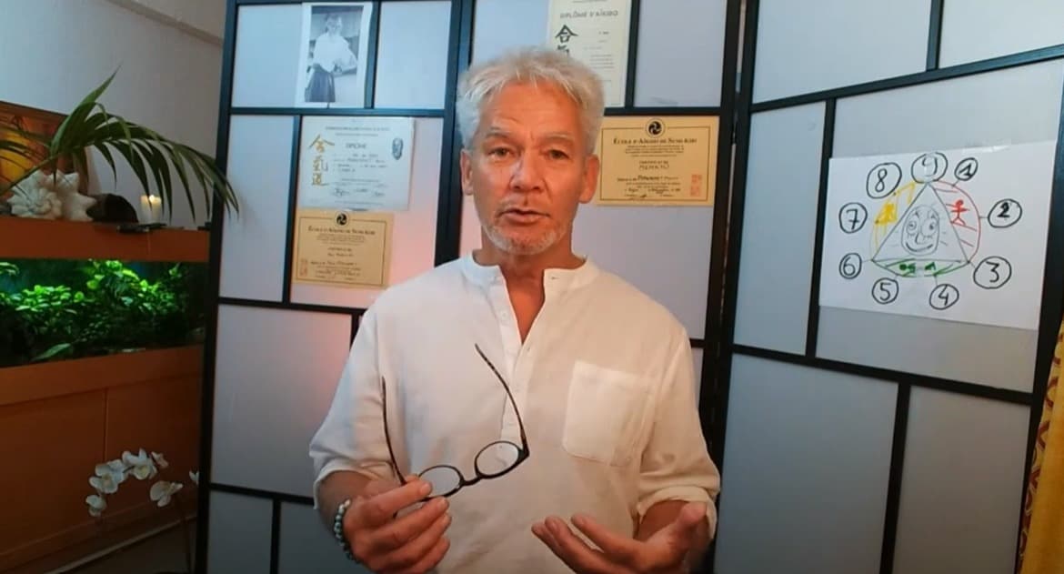 Pierre Pyronnet devant ses diplômes Aïkido et le schéma des 9 piliers